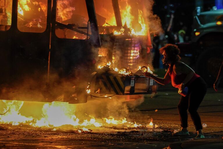 Протестующий возле горящего мусоровоза во время протестов в Кеноша, штат Висконсин Протестующий возле горящего мусоровоза во время протестов в Кеноша, штат Висконсин