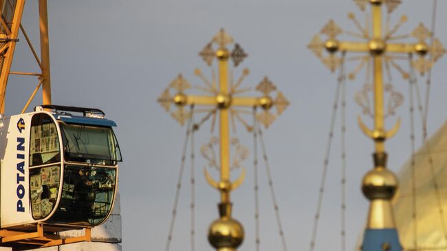 Кабина строительного крана и кресты на куполах храма