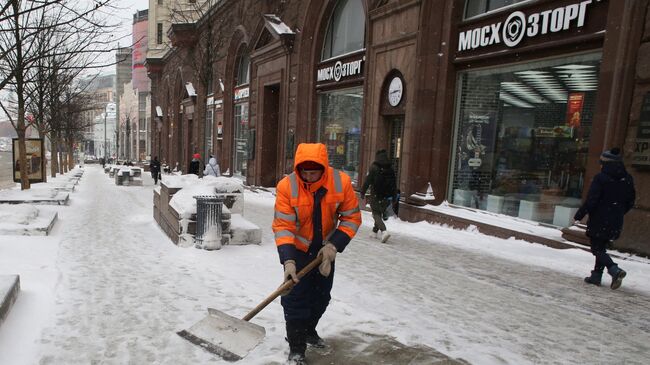Сотрудник коммунальных служб убирает последствия снегопада на Тверской улице в Москве
